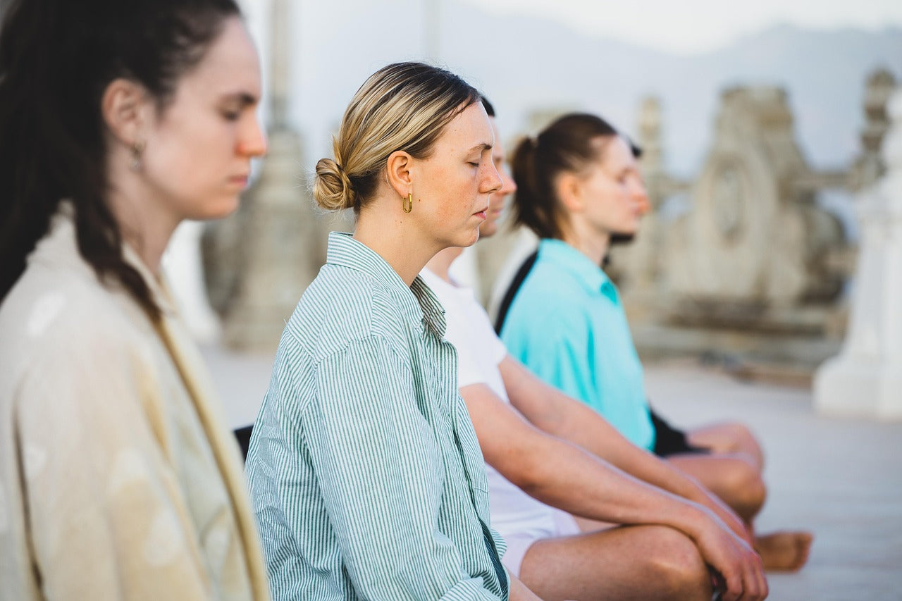Groupe de femmes en méditation, illustrant l’impact du stress et de la détente sur l’équilibre intime à la ménopause.