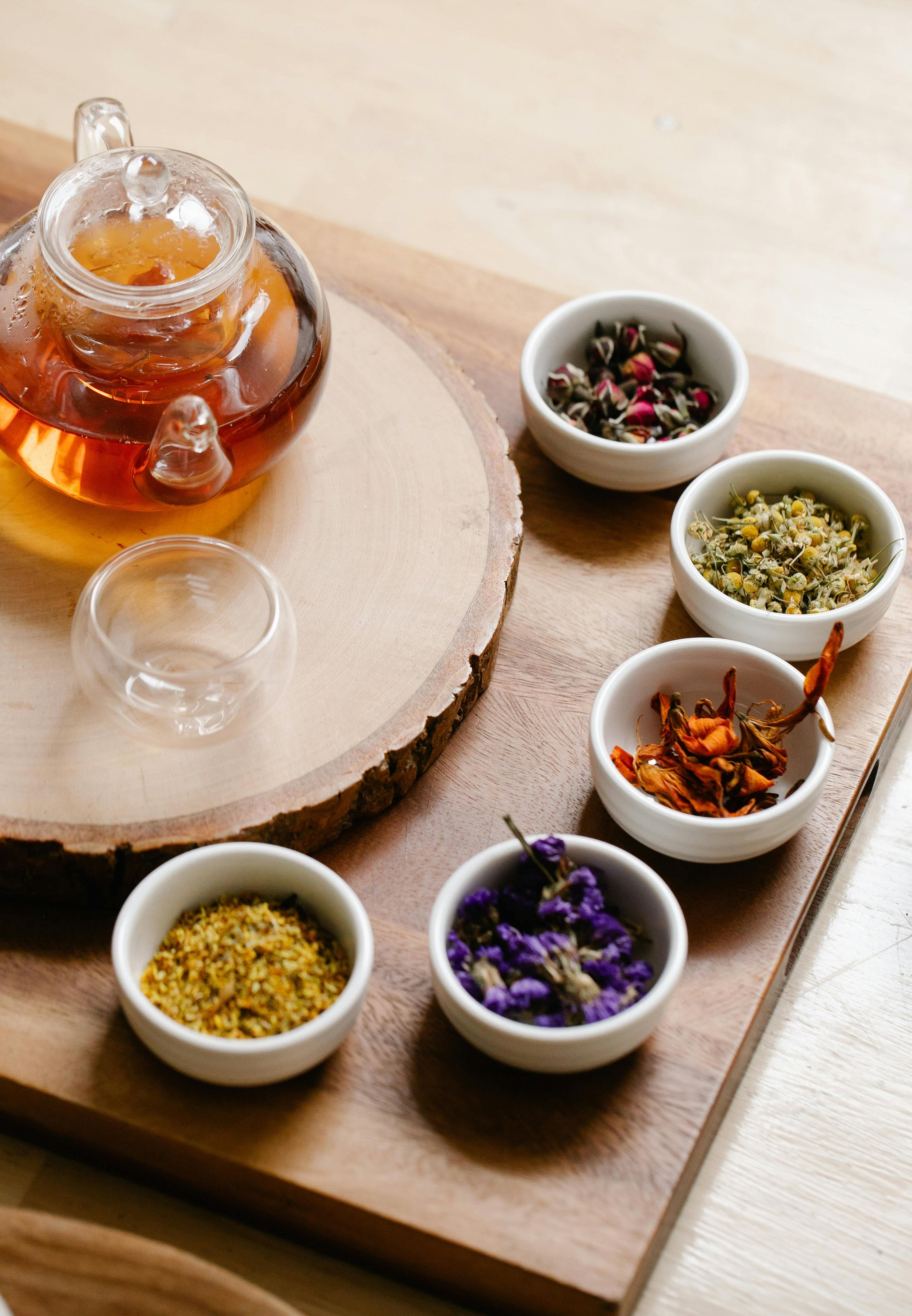 Sélection de plantes séchées et théière en verre, montrant les ingrédients naturels des infusions pour SPM, sommeil ou libido.